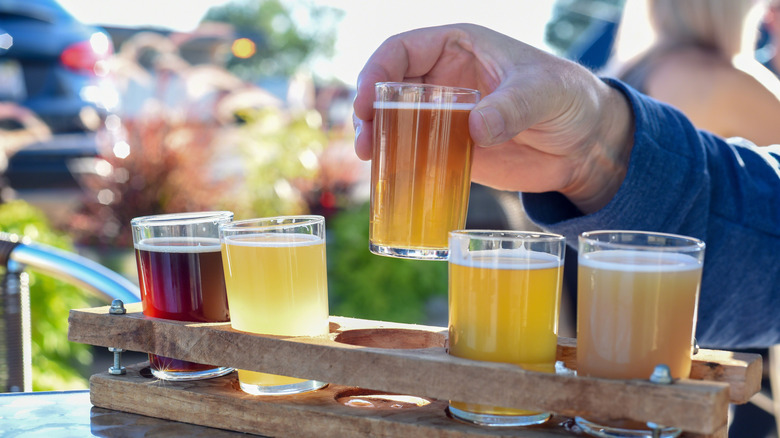 hand samples multiple beers in beer flight outside
