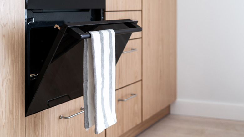 A white checkered dish towel hanging on the oven door