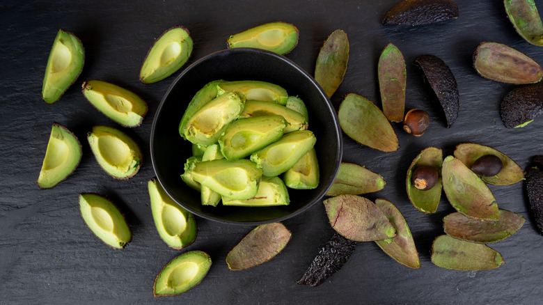 avocados in a bowl with the shells outside the bowl