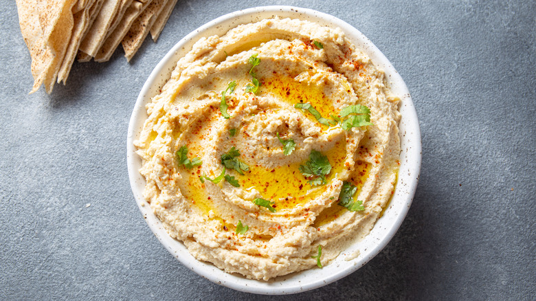 Hummus in a white dish on a gray surface.