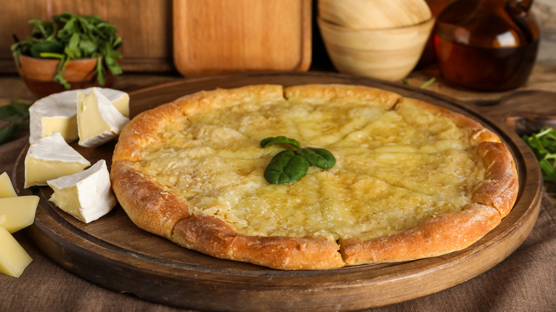 pieces of brie cheese beside a whole sliced pizza