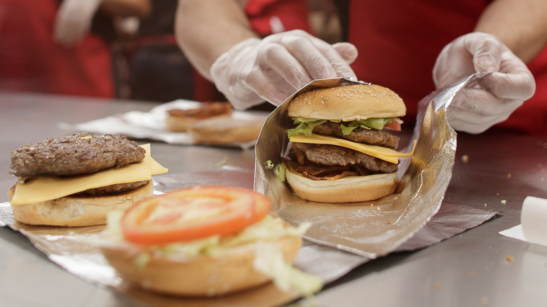 Five Guys employee wrapping a hamburger in aluminum foil