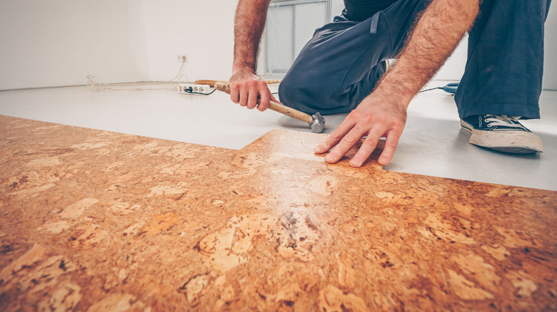 Someone on the ground installing cork floor tiles