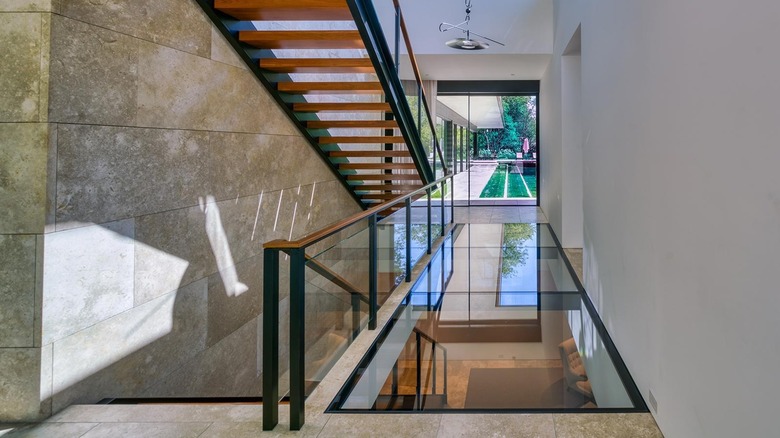 A clear glass walkway inside of someone's home near the staircase
