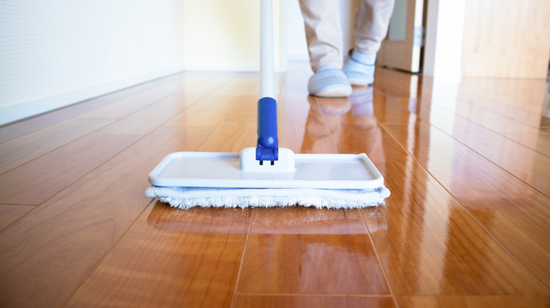 A microfiber mop being used to apply wax to a polished wood floor