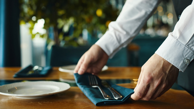 close up of a waiter setting up place setting in a restaurant