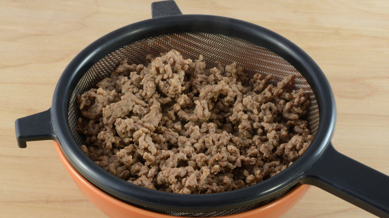 Straining the fat off cooked ground beef with a strainer over a bowl