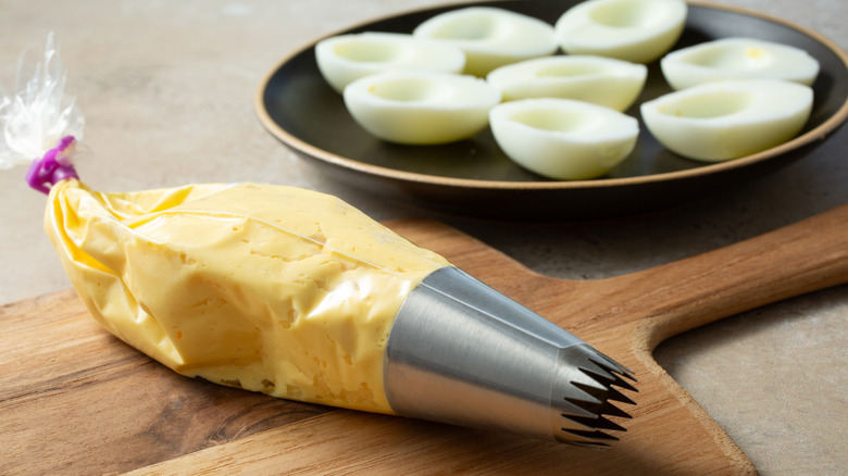empty deviled egg whites and filling inside a piping bag ready to be piped