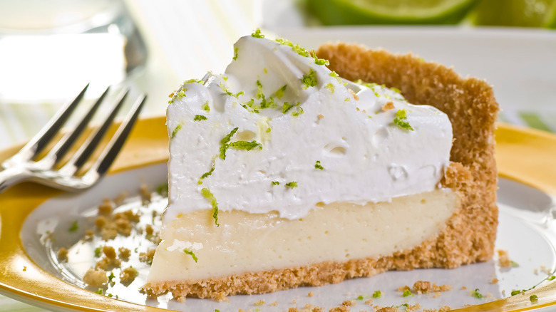 Key lime pie slice plated, fork, thick whipped cream