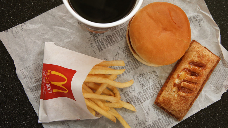 A tray with McDonald's apple pie, a burger, a cup of coffee, and a small bag of fries