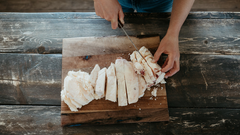 hands slicing up beef tallow on a wooden board