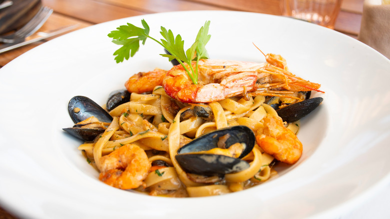 Plate of seafood pasta featuring shrimp, mussels, and fettuccine noodles.