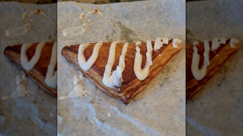 Arby's cherry turnover drizzled with white icing on parchment paper wrapping, with mirror borders