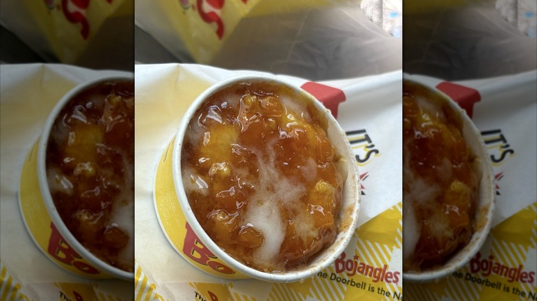 A cup of Bojangles' peach cobbler on a Bojangles paper bag, with mirror border