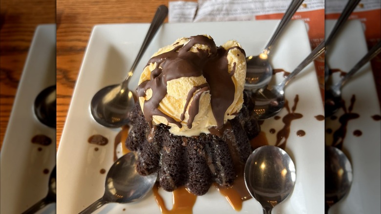 Chili's Molten Lava Cake on a white plate with several spoons, on a wooden dining table