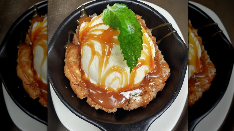 Outback Steakhouse salted caramel cookie skillet on a white dish topped with mint leaf and caramel drizzle, with mirror border