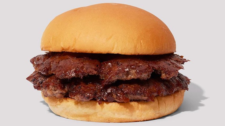 Two beef smashed patties are sandwiched between a soft, fresh hamburger bun, on a creamy gray background from Shake Shack