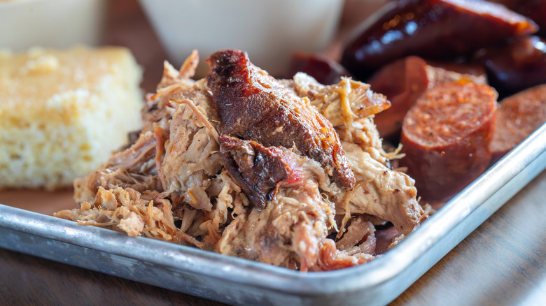 A tray of barbecue with a pile of juicy pulled pork at the center