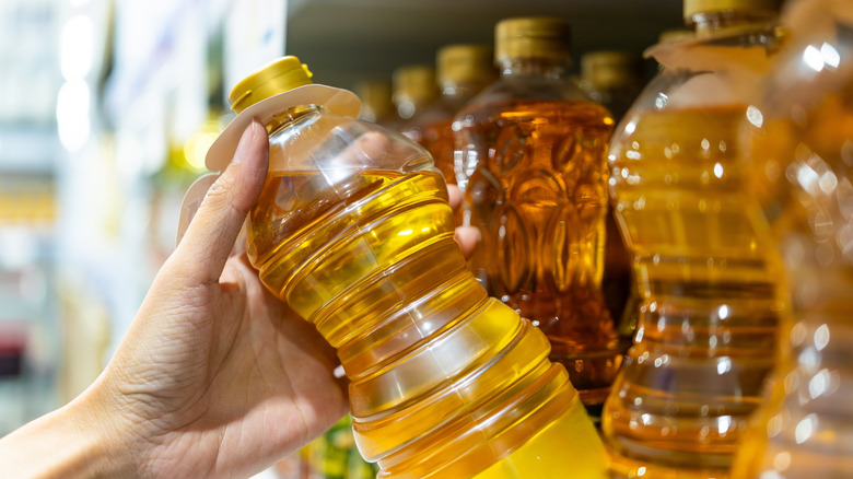 Hand grabbing a bottle of vegetable oil from the store shelf