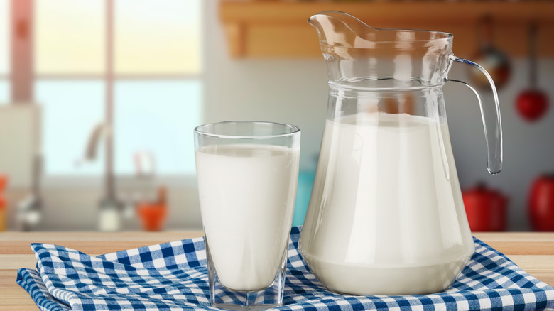 A jug and glass of milk on a blue plaid kitchen towel