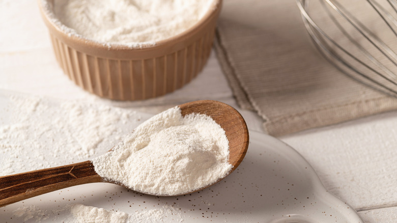 Flour in a ramekin and on a wooden spoon