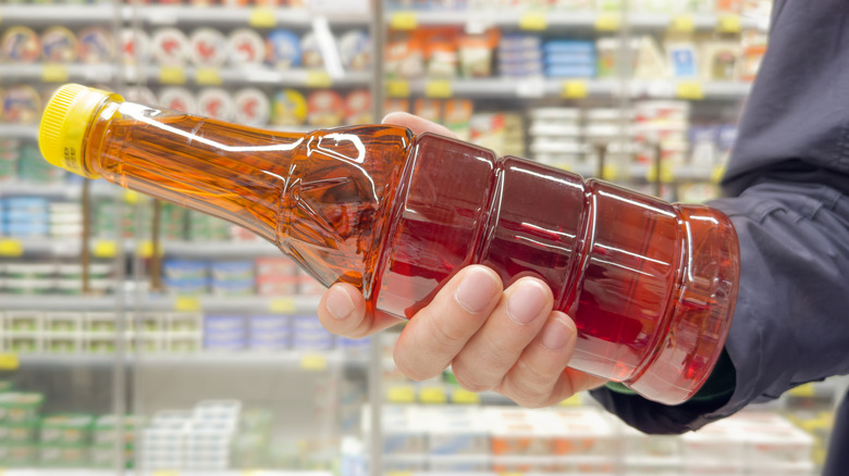 Hand holding a bottle of vinegar in a store