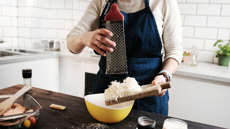 Person grating fresh cheese bowl