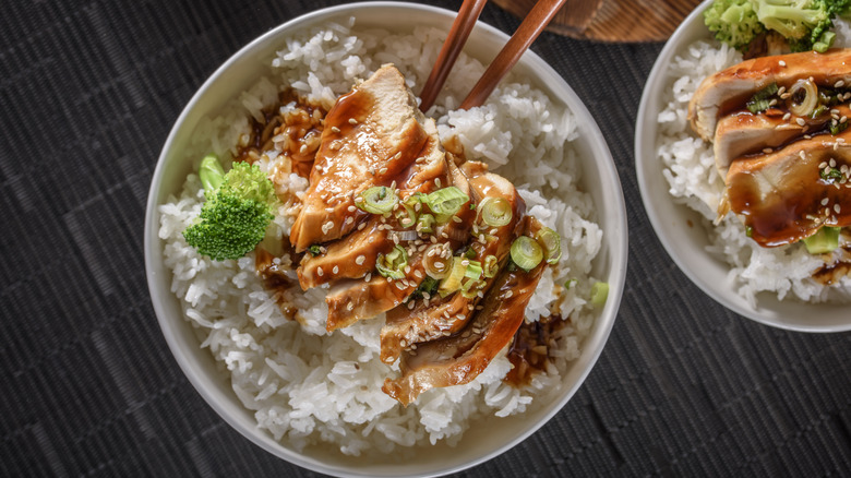 Two chicken terryaki bowls with sauce, sesame seeds