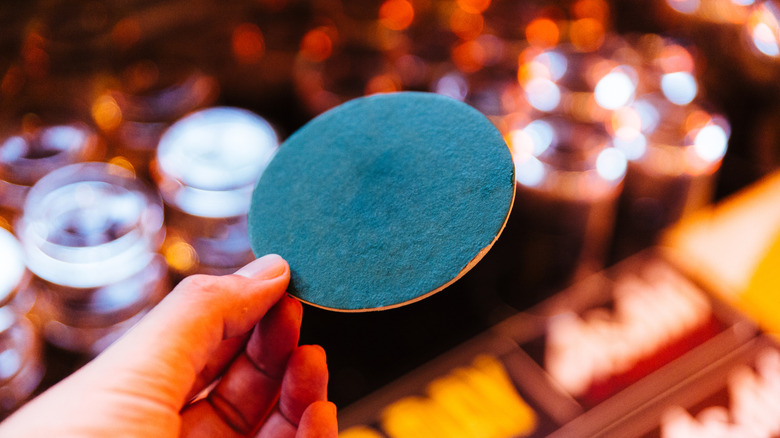hand holding green paper coaster against blurry restaurant background