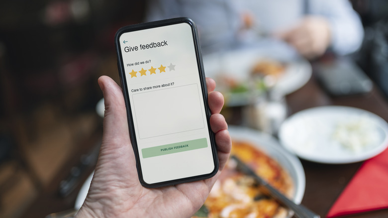 Person holding smart phone with restaurant rating app