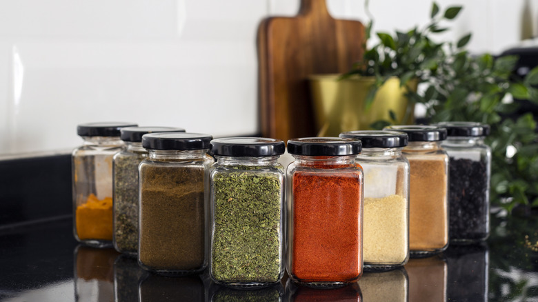 Various spices placed on a kitchen counter in glass containers