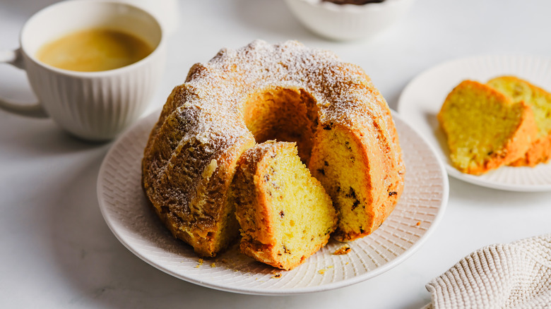 A Bundt cake with a slice cut out with a cup of coffee next to it
