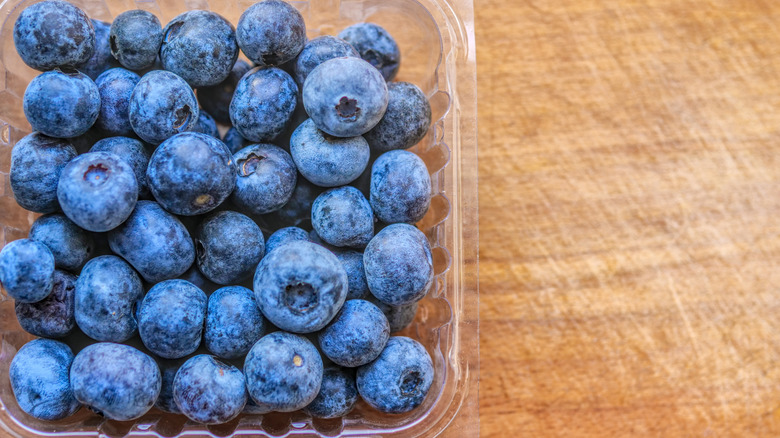 Punnet of blueberries on wooden surface