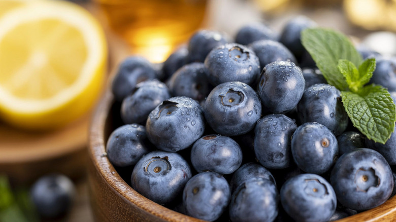Blueberries in wooden bowl with sprig of mint