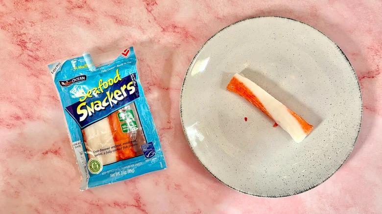 Pack of Trans Ocean Seafood Snackers with one next to it on a plate