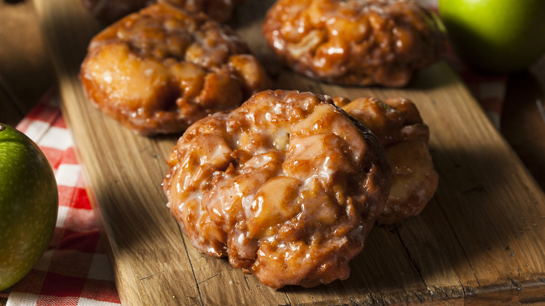 glazed apple fritters on a wooden board