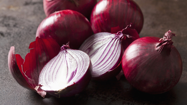 Pile of red onions, one is sliced