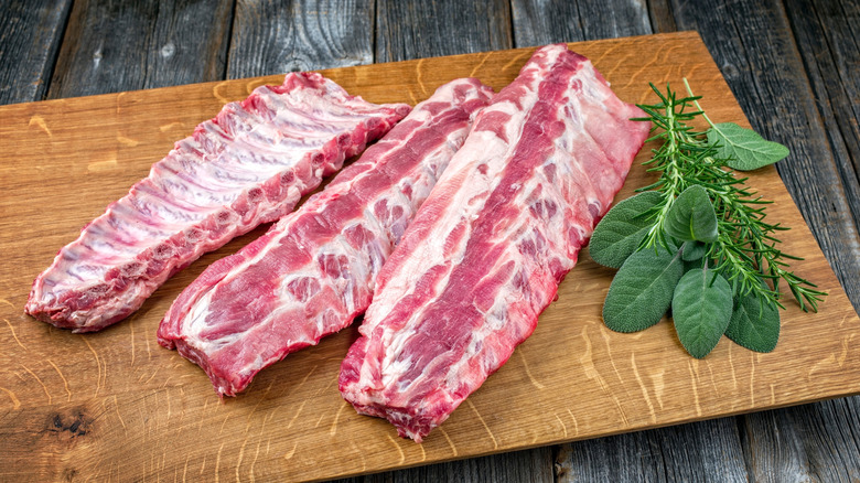 Three racks of pork ribs on wooden cutting board