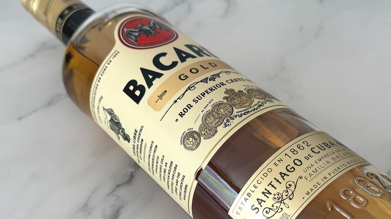 Close-up of bottle of Bacardi Gold laying down on marble surface