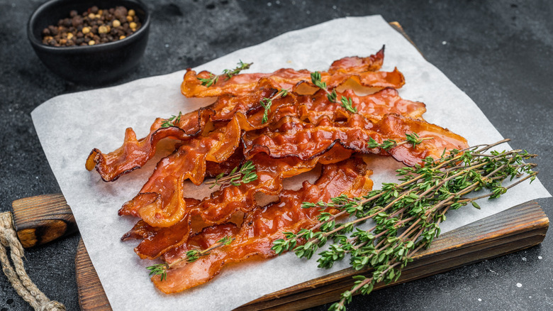 Several slices of cooked bacon on a wood board