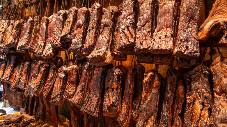 Sides of bacon hanging in a smokehouse