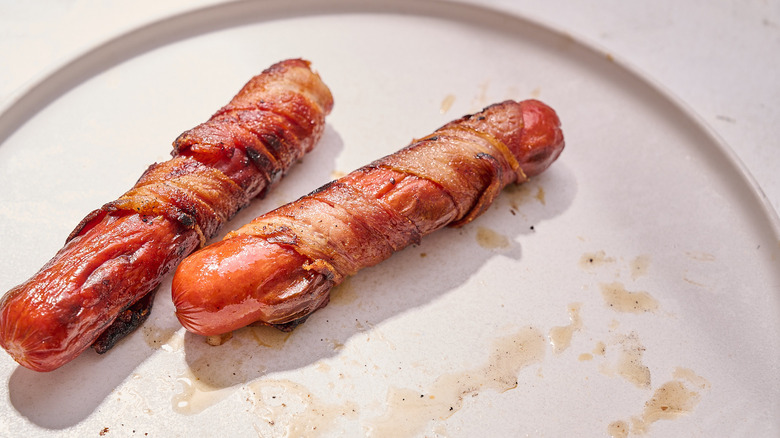 bacon wrapped hot dogs on a plate