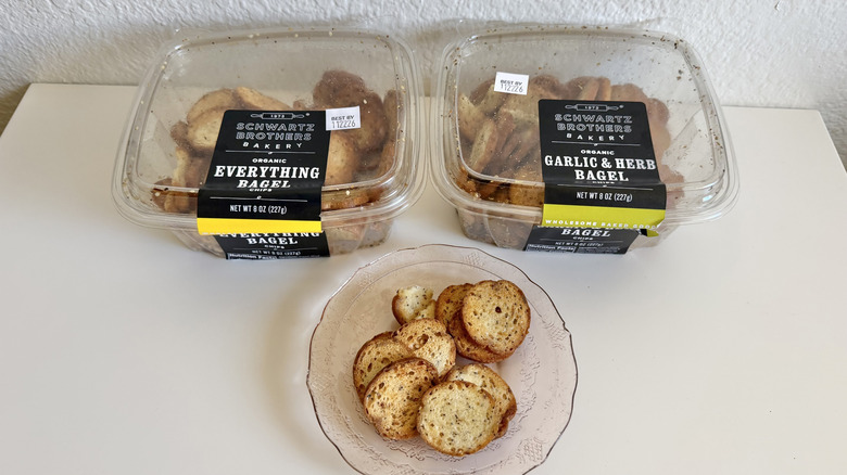Plastic containers of Schwartz Brothers Bakery bagel chips on a table with chips on a plate