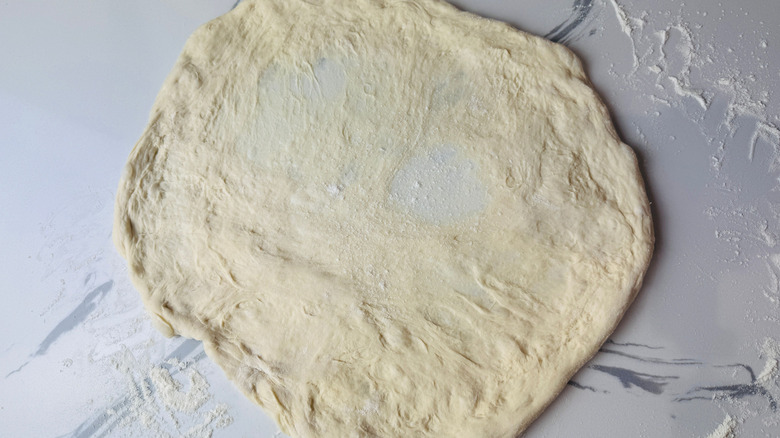 Stretched out pizza dough round on countertop