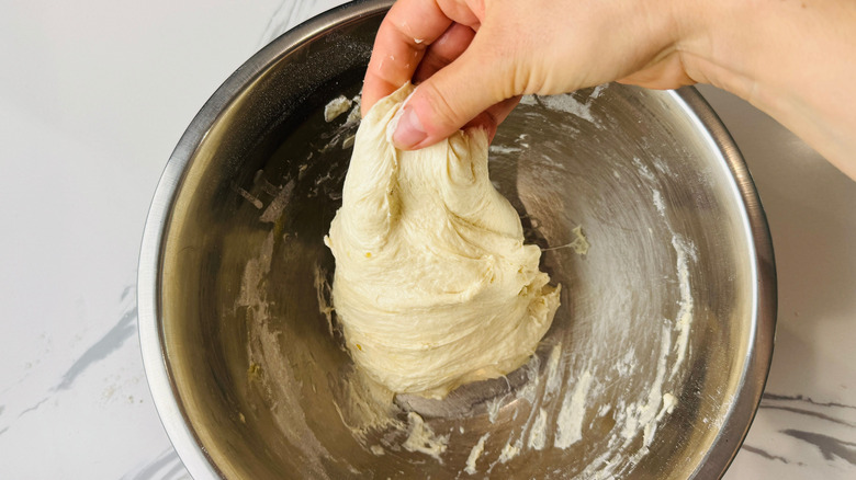 Hand stretching dough in bowl
