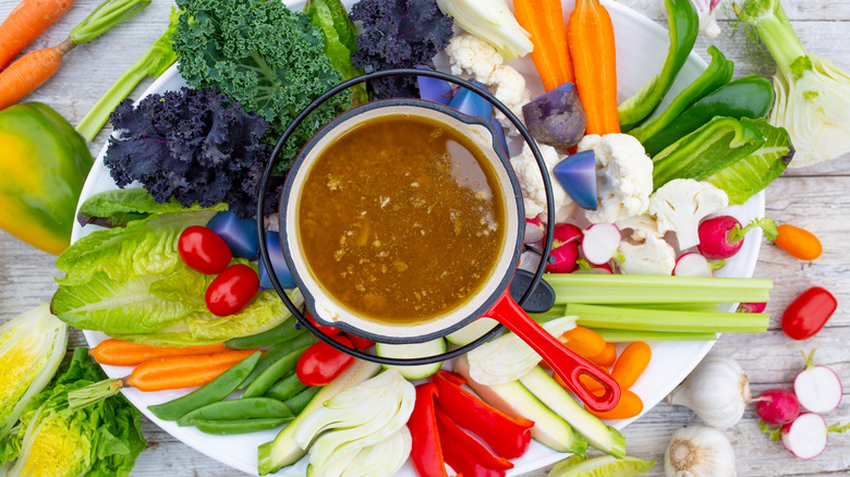 Cup of bagna cauda surrounded by veggies
