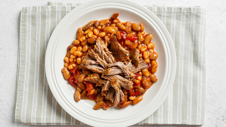 A plate of baked beans and shredded meat