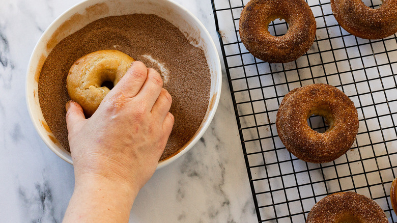 Dipping donuts into cinnamon sugar.