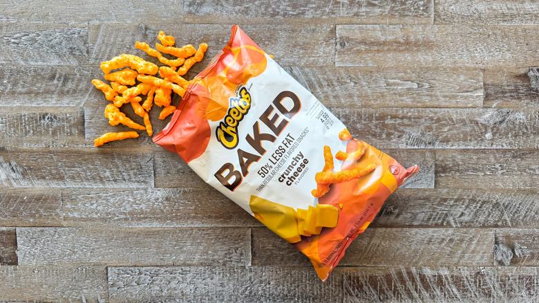 Cheetos baked crunchy cheese chips bag with chips spilling out on wooden surface
