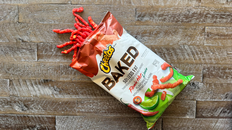 Cheetos baked Flamin' Hot Límón chips bag with chips spilling out on wooden surface